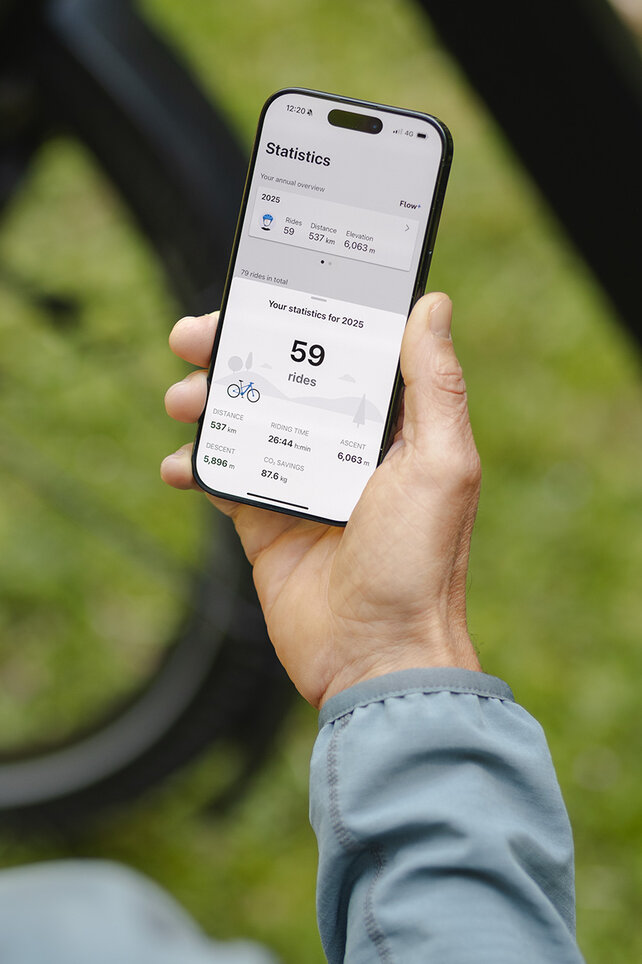 Iemand houdt een smartphone in de hand en bekijkt de statistieken in de eBike Flow-app.