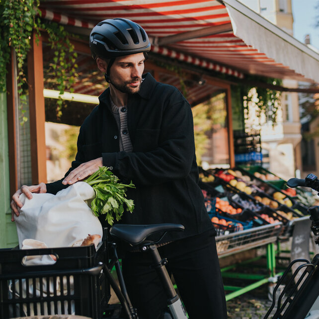 Ein Mann mit Helm belädt sein eCargo Bike mit Einkäufen.