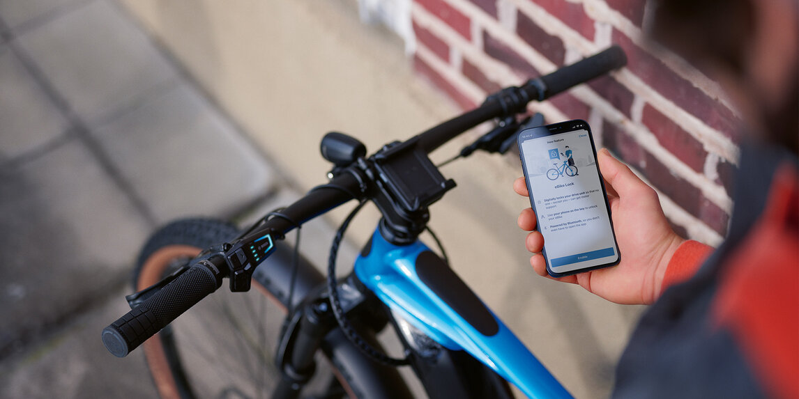 En person sitter på sin eBike med sin smartphone i handen och låser upp eBiken med eBike Lock.