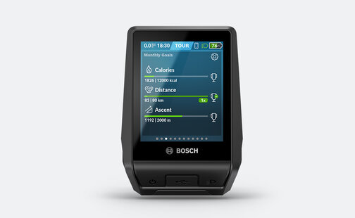 The [eBike] [on-board computer] [Nyon] with the [display] turned on, which shows the monthly goals for calories, distance, and [ascent].
