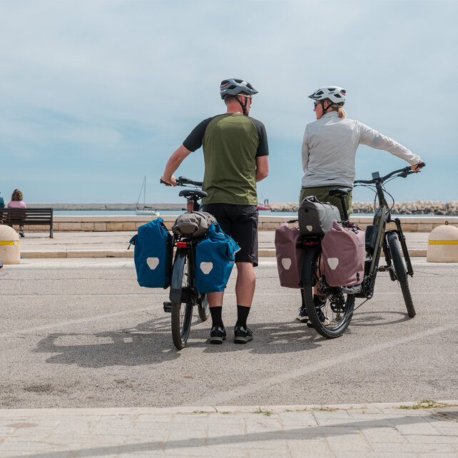 En kvinna och en man står vid vägkanten med sina fullastade eTrekking-bikes.
