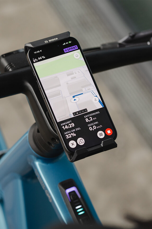 Nahaufnahme eines SmartphoneGrip Verticals, das an einem Lenker befestigt ist. Das Smartphone befindet sich im Navigationsmodus und zeigt eine Routenführung an.