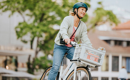 eBike-Fahrerin fährt mit ihren Einkäufen in einem Korb durch die Stadt.