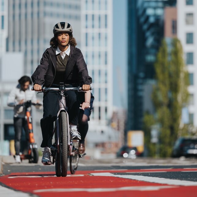 A woman rides her eBike on a red bike lane in the city.
