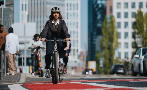 Une femme circule sur sa VAE sur une piste cyclable rouge en ville.