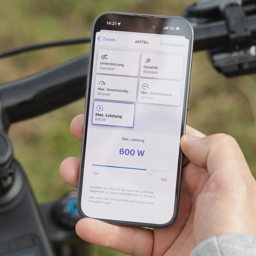 Nahaufnahme eines Smartphones, das die eBike Flow App zur Individualisierung der Fahrmodi zeigt. Der Bildschirm stellt die Einstellungsoptionen für den eMTB+ Modus dar, bei dem der Wert für die maximale Leistung über einen Schieberegler auf 600 Watt justiert wird.