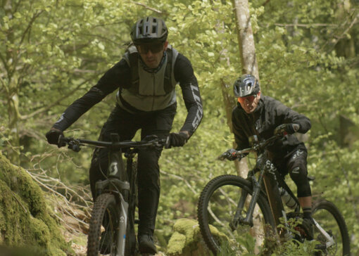 Deux Vététiste se suivent dans un environnement forestier.
