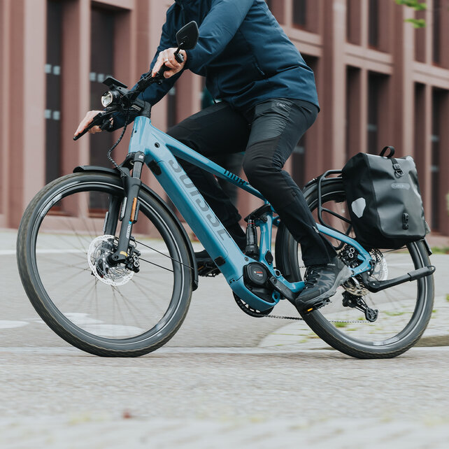 A man is riding his eBike through a right-hand curve.