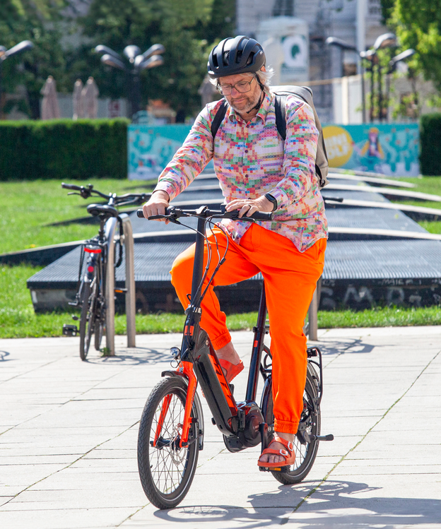 Ein bunt gekleideter Mann fährt in städtischer Umgebung ein eBike.