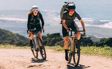 Two eBike riders on their eBikes in the mountains, each with hiking backpacks.