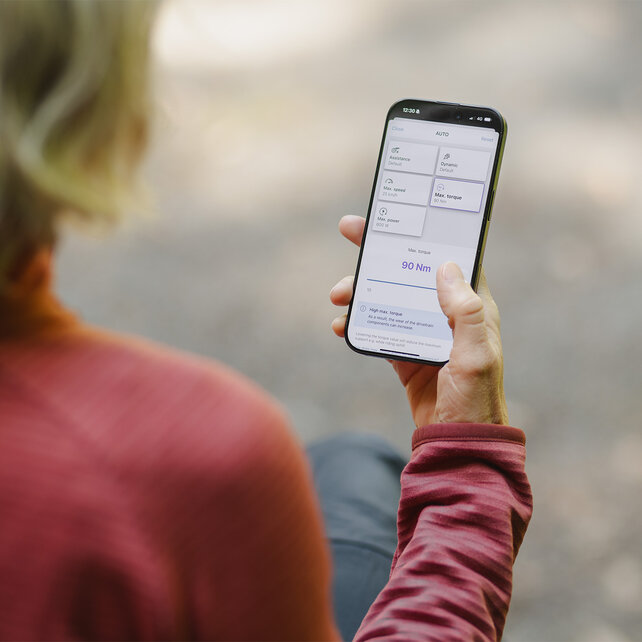 Blick über die Schulter einer Frau, die in der eBike Flow App die Leistungswerte individuell einstellt.