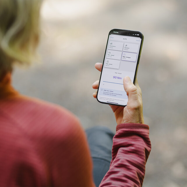 View over the shoulder of a woman who individually adjusts the performance values in the eBike Flow app.