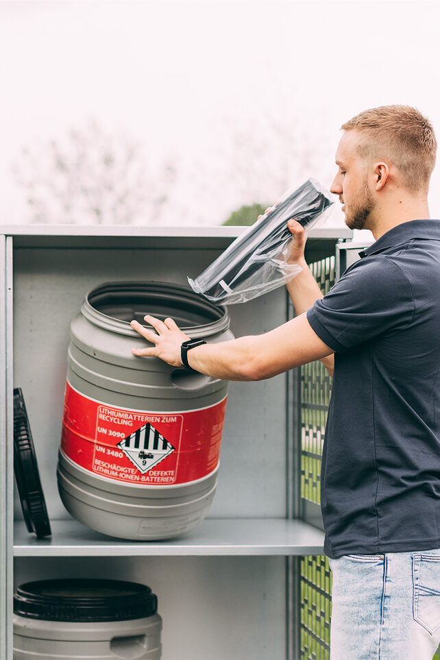 A Bosch service employee disposes of an eBike battery in accordance with the regulations in a container with a red warning label that reads 'Lithium batteries for recycling' UN 3090 UN 3480 Damaged/Defective lithium-ion batteries.