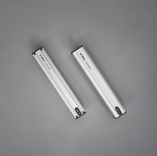 Deux batteries sont allongées l’un à côté de l’autre sur un sol gris.